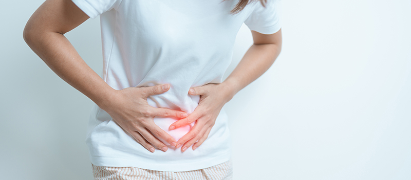 Woman holding her lower abdomen with a pained expression, indicating discomfort or stomach pain