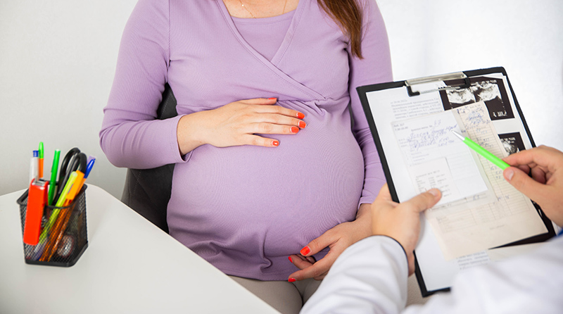 A pregnant woman receiving a consultation from a gynaecologist.